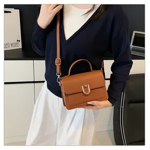 Détail d'un sac à main marron en cuir grainé avec une boucle dorée en forme de U