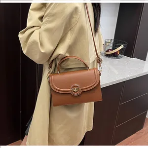 Détail du sac à main marron foncé avec motif litchi et fermoir rotatif en métal arrondi