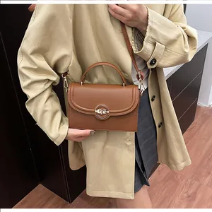 Détail d'un sac à main marron grainé avec un fermoir rotatif en métal doré élégant