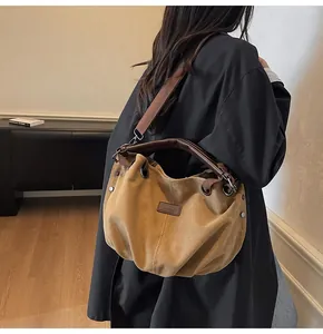 Detalle del bolso tote de lona vintage con asas de cuero marrón y remaches