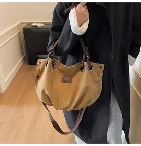 Detalle de bolso tote de lona vintage con asas de cuero, remaches y correa ajustable