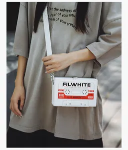Detalle de un bolso bandolera blanco con diseño de casete vintage y correa ancha blanca