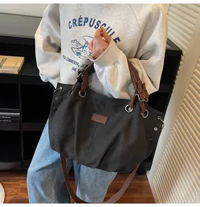 Detalle del bolso tote de lona con correas de cuero marrón y ojales metálicos
