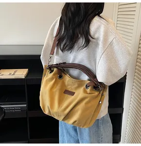 Detalle del bolso tote de lona amarillo mostaza con asas de cuero y remaches en modelo