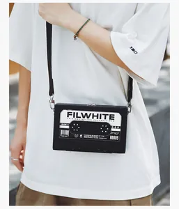 Detalle de un bolso de cámara retro negro con diseño de casete y cierre de metal plateado