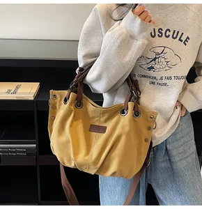 Detalle de bolso tote de lona amarilla con correas marrones y acentos de ojales metálicos