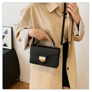 Détail du sac à bandoulière noir en cuir grainé avec boucle dorée et bandoulière