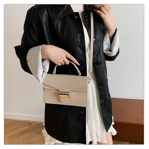 Gros plan du sac beige en cuir à grain de litchi avec boucle dorée élégante