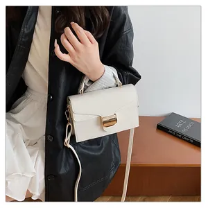Détail du sac bandoulière crème en cuir litchi avec boucle dorée et poignée élégante
