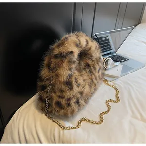 Gros plan du sac à main en peluche léopard avec chaîne en métal doré sur un lit blanc