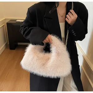 Détail d'un sac à main en peluche rose clair avec chaîne dorée sur un mannequin en blazer