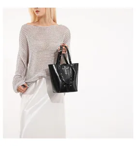 Close-up of black glossy bucket bag with silver gothic cross and rivet details