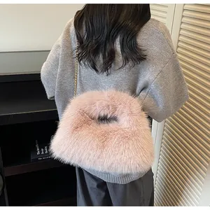 Détail du sac à main en peluche rose avec chaîne dorée sur fond de pull gris en maille
