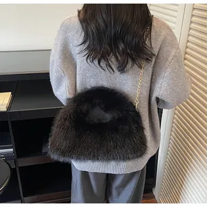 Vue détaillée du sac en fausse fourrure noire avec chaîne dorée sur l'épaule du modèle