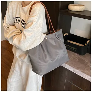 Detailed top view of large grey nylon tote bag with brown leather straps for daily use