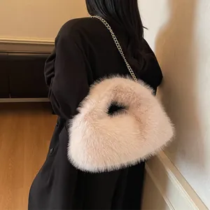 Sac bandoulière en fausse fourrure rose avec chaîne dorée porté sur un manteau noir