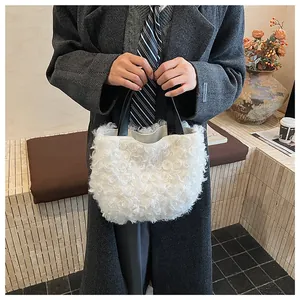 Detail of white curly faux fur tote bag with black leather handles held by a model