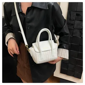 Primer plano del mini bolso blanco con textura tejida y detalles metálicos dorados