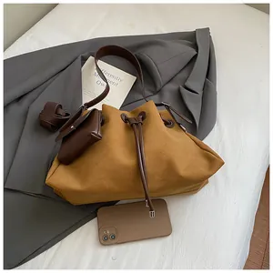 Dettaglio della borsa a secchiello in camoscio con coulisse in pelle e mini pochette