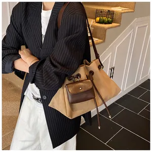 Dettaglio della borsa a secchiello kaki con tracolla in pelle marrone e mini pochette su modella