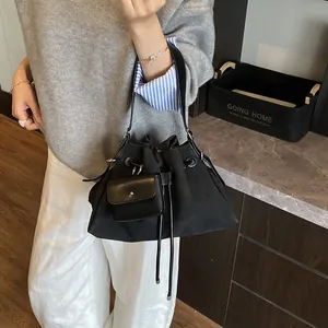 Borsa a secchiello in tela nera opaca con chiusura a coulisse e mini ciondolo borsa