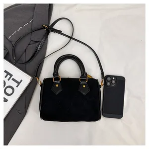 Flat lay of black suede pillow bag with quilted stitching and gold metal hardware