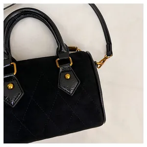 Close-up of black matte suede pillow bag with quilted patterns and gold zippers