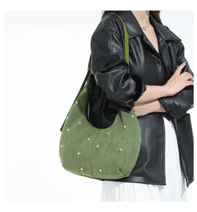 Sac croissant vert olive avec clous dorés en daim givré porté par un mannequin en studio