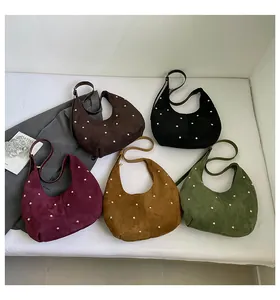 Détail de cinq sacs hobo en daim avec clous dorés aux couleurs terreuses d'automne