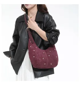 Détail du sac hobo bordeaux avec clous dorés et texture suédée mate porté par un mannequin