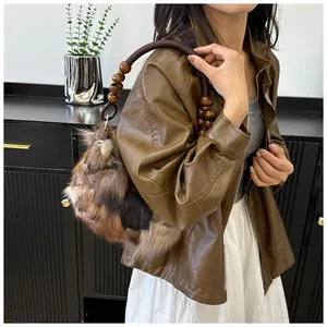 Detail of faux fox fur underarm bag with contrast stitching and wooden bead shoulder strap
