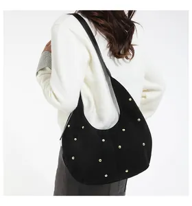 Gros plan détaillé d'un sac demi-lune en daim noir avec rivets dorés élégants