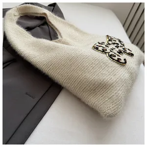 Detalle de bolso de punto beige con un lazo de leopardo y borde de lentejuelas