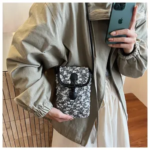 Detail of tweed crossbody mini bag with leather toggle closure on a casual outfit