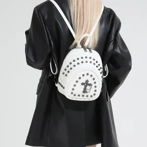 Sac à dos blanc en cuir PU avec croix gothique et rivets porté par un mannequin en manteau