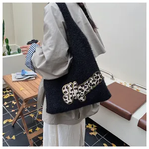 Bolso tote de felpa negro con parche de letras de leopardo en un entorno otoñal