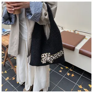 Detalle de bolso de hombro de felpa negra con parche de letra leopardo en tejido suave