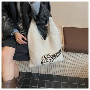 Detalle de textura de bolso tote de punto blanco con parche de letra en estampado de leopardo