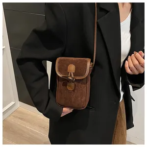Detail of dark brown suede shoulder bag with vintage horn buckle and leather piping