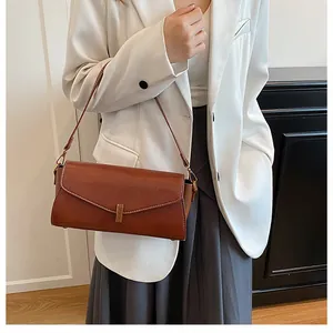 Detailed view of dark brown lychee grain leather handbag with stitching and gold buckle