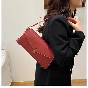 Red lychee texture leather shoulder bag with a gold buckle shown on a black suit jacket