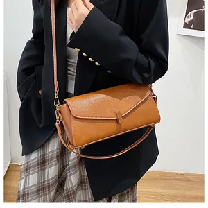 Detail of a brown lychee pattern leather shoulder bag with a sleek minimalist metal clasp