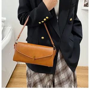 Detail of caramel lychee grain leather handbag with gold rectangular buckle and fine stitching