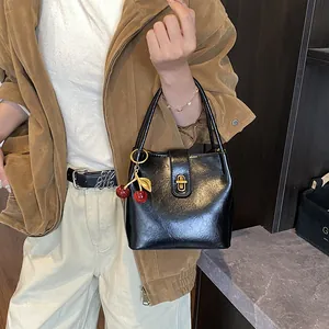 Classic black bucket bag with gold clasp and red cherry charm on handle