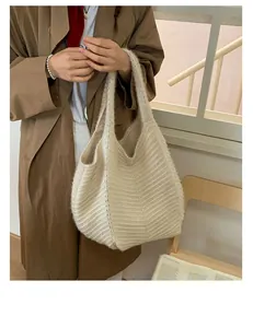 Close-up of cream knit tote bag with vertical texture paired with a brown trench coat