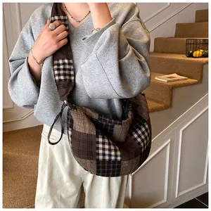 Model wearing a large checkered canvas hobo bag in a retro British brown and black style