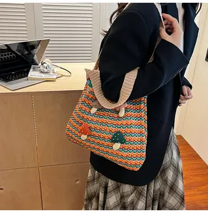 Detail of colorful striped crochet tote bag with mushroom appliqués worn by a model