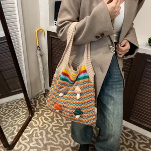 Colorful striped crochet tote bag with mushroom patches worn over the shoulder