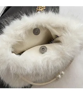Close-up of white plush handbag featuring a magnetic snap closure and pearl strap detail
