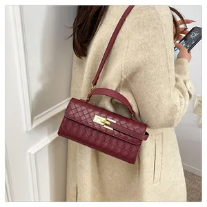 Close-up of wine red woven leather handbag with gold metal clasp on a beige coat